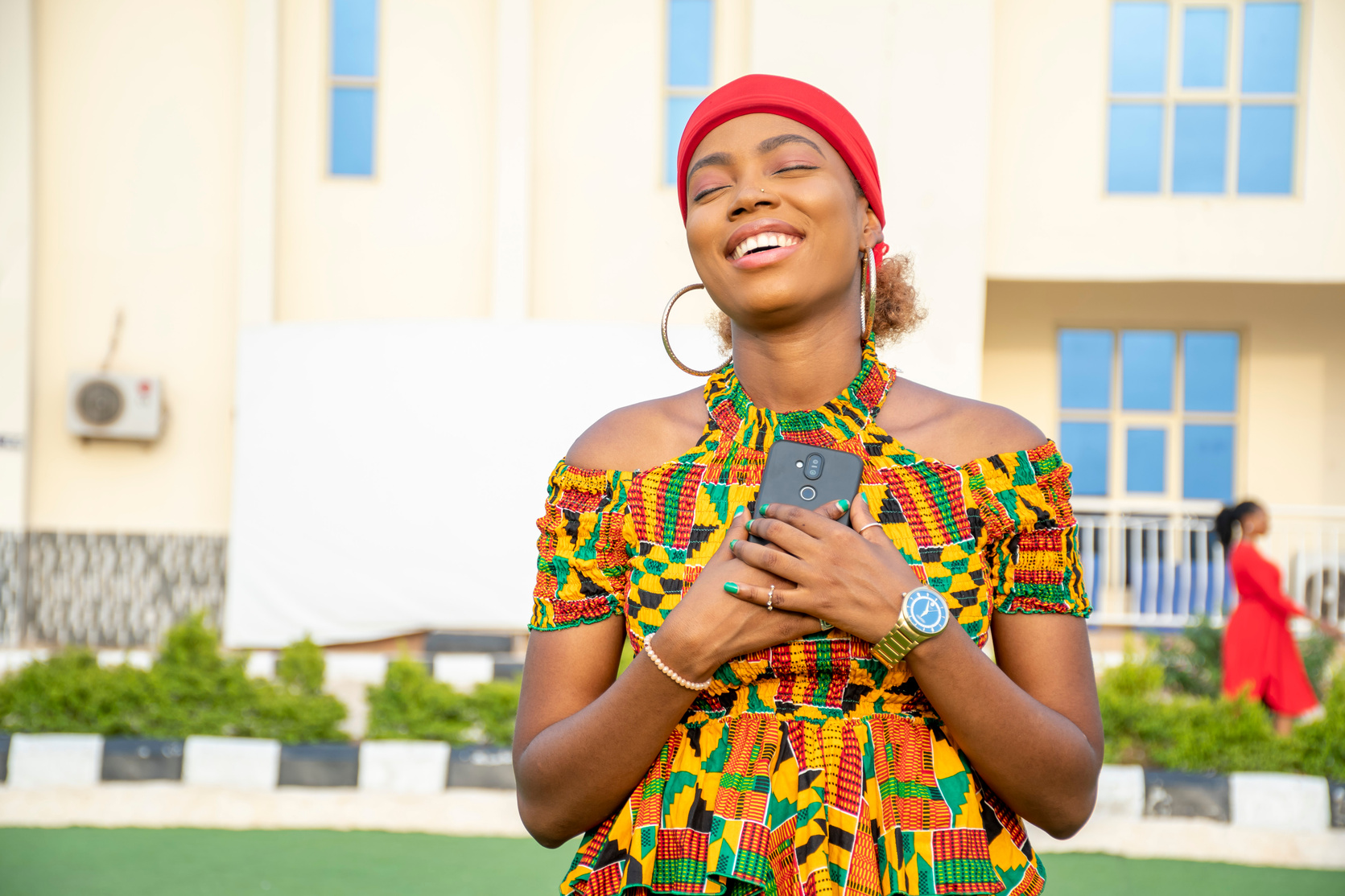 a beautiful african lady holding her phone to her chest filled with joy